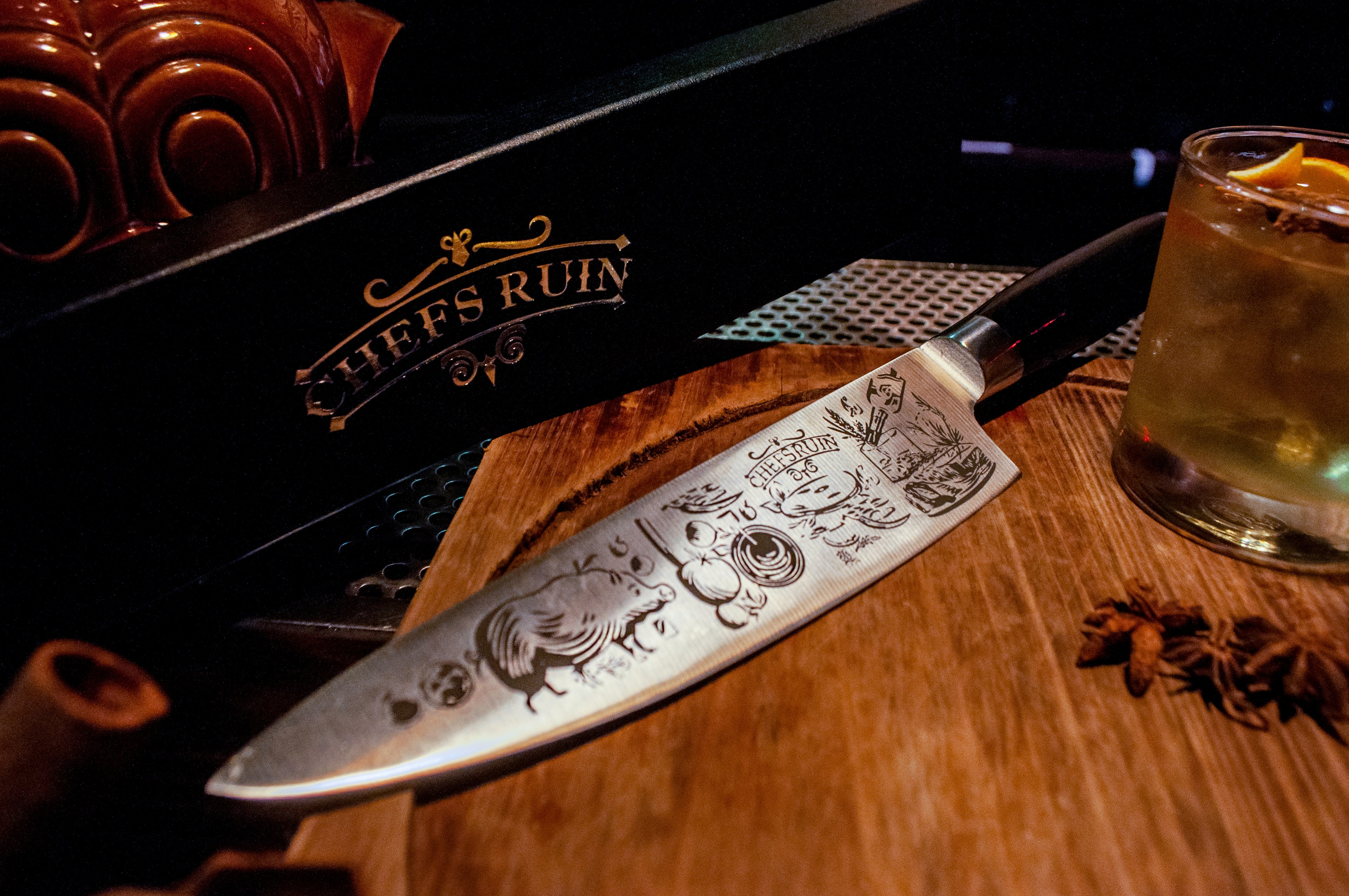 ChefsRuin chefs knife on a cutting board around various ingredients, herbs and spices