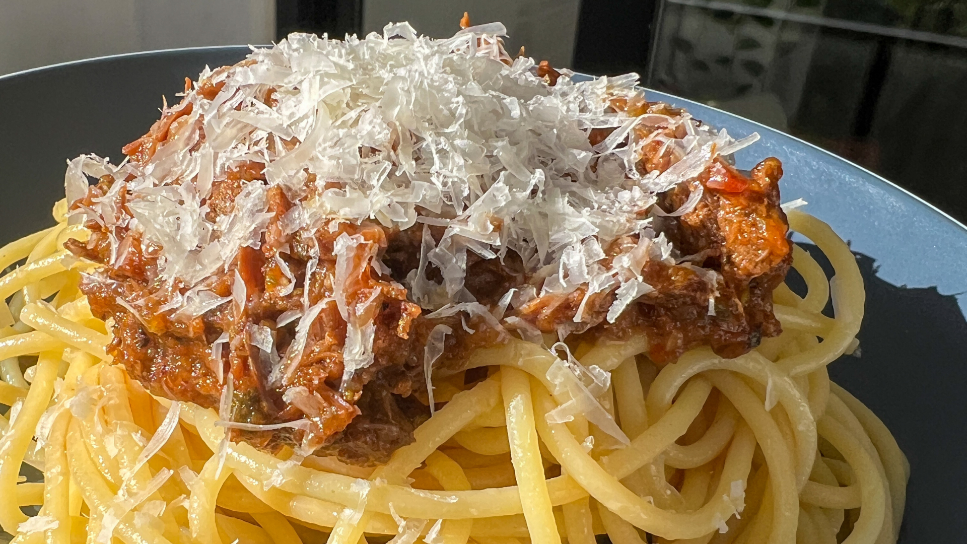a plate of spaghetti with kangaroo ragu and parmesan cheese