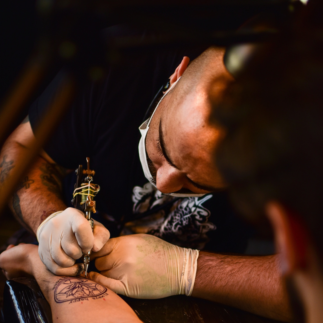 tattoo artist tattooing a compass onto a customers wrist 
